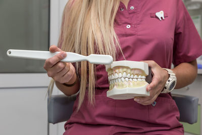 Midsection of dentist cleaning dentures in clinic