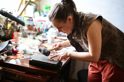 Home workshop girl master rubber hammer knocks on a copper plate, the concept of creativity 