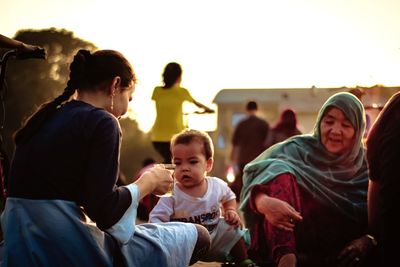 Group of people sitting against sky during sunset