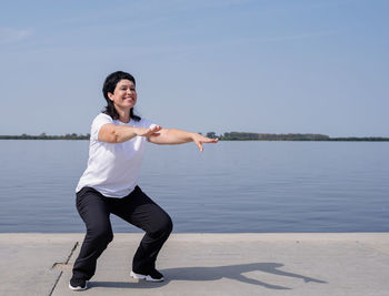 Full length of smiling man standing in lake against sky