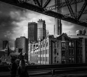 People on bridge against buildings in city