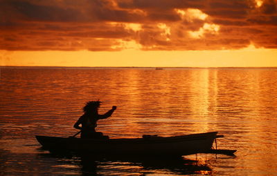 Woman paddling on sea at sunset