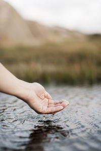 Cropped image of woman's hand over river