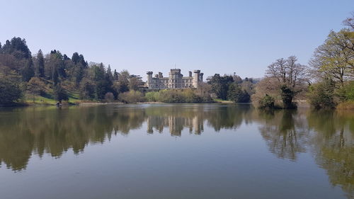 Scenic view of lake by buildings against clear sky