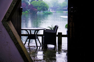 Empty chairs and table by lake