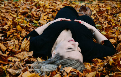 Woman lying on autumn leaves at park