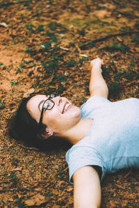 High angle view of smiling young woman while lying down on field
