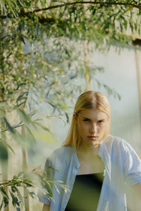 Portrait of young woman standing against plants