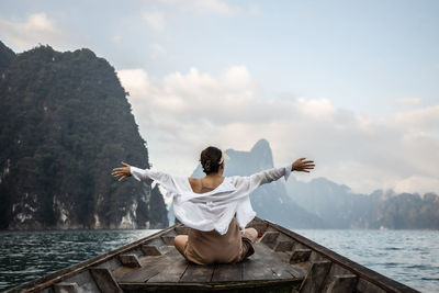 An asian woman in a white shirt sits in front of a boat trip in thailand. amazing thailand.