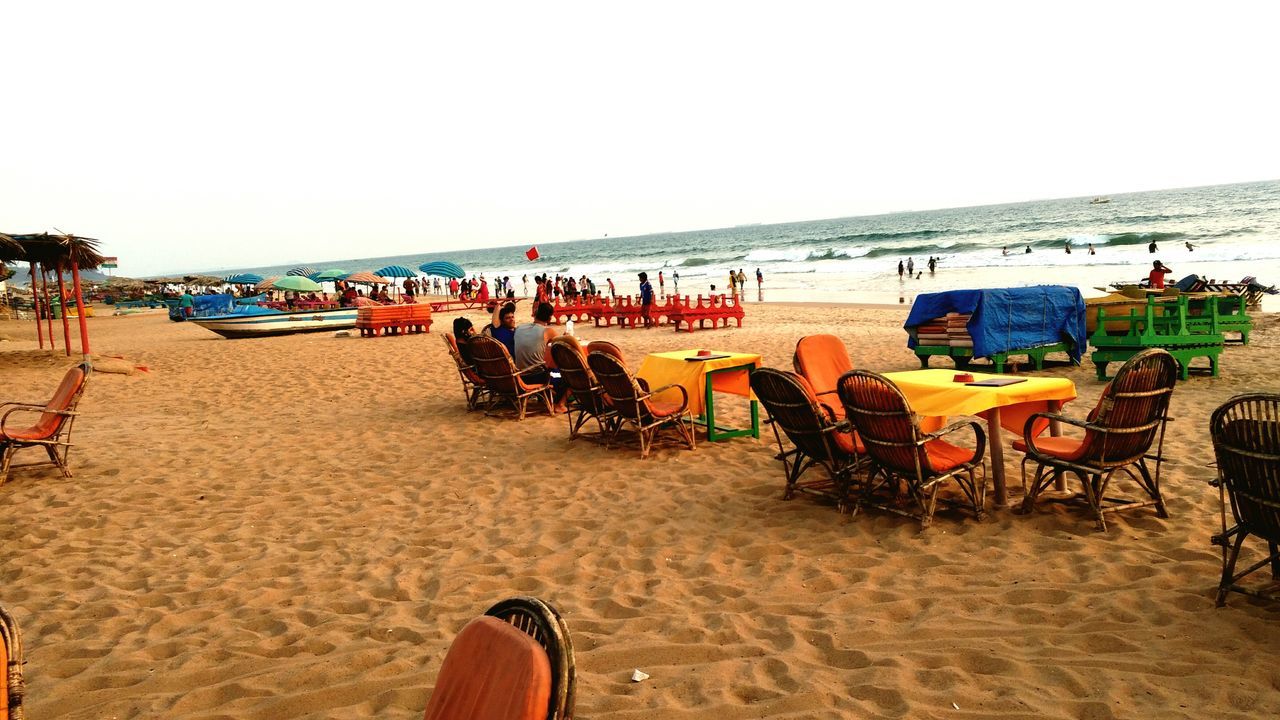 beach, sand, sea, shore, vacations, chair, horizon over water, nature, clear sky, water, large group of people, scenics, day, outdoors, beauty in nature, real people, sky, sand dune, people