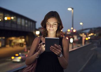 Germany, hamburg, young woman in the street using digital tablet on the move