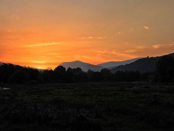 Scenic view of silhouette field against orange sky