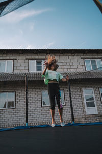 Full length of young woman standing against building