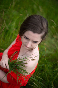 Portrait of young woman holding red leaf on field