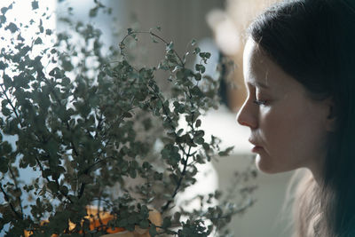 A young woman in a green linen dress with potted plants