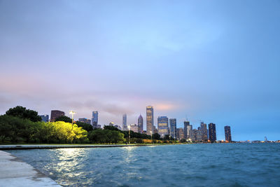 Sea by buildings against sky in city