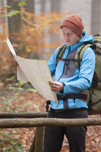 Midsection of man holding hat while standing outdoors