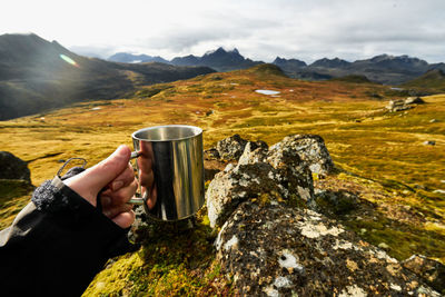 Point of view of hiking man holding a cup of coffee on trail in moskenesoy lofoten norway