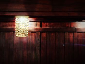 Low angle view of illuminated light bulb hanging on ceiling