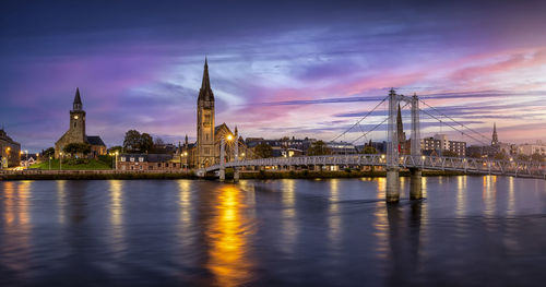 Bridge over river against sky at sunset