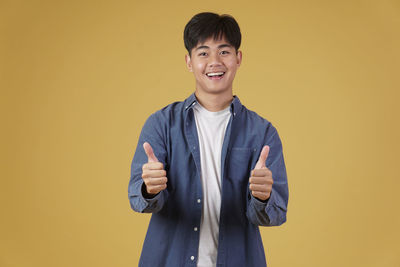 Portrait of a smiling young man against yellow background