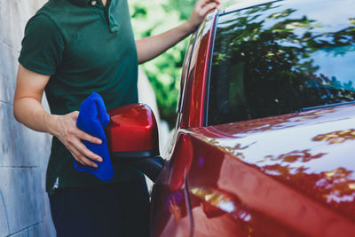 Midsection of man cleaning red car