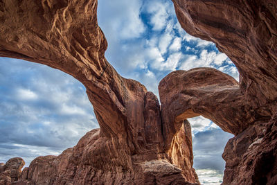 Low angle view of rock formations against cloudy sky