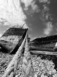 Abandoned boat on beach against sky