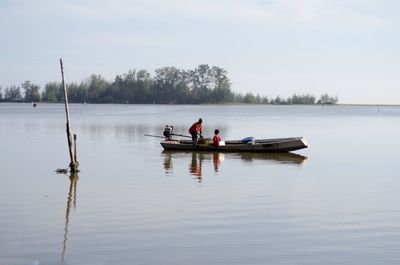 Men in boat on lake against sky