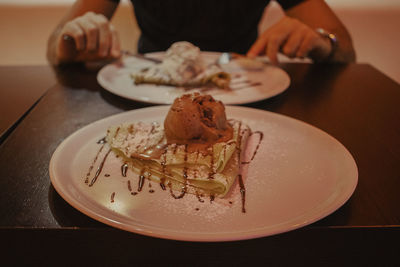 Midsection of person having dessert on table