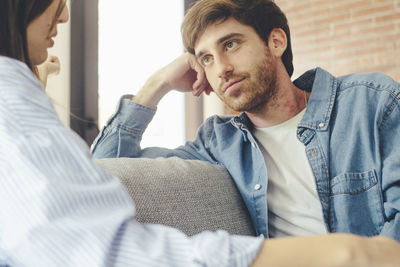 Portrait of young man sitting on sofa at home