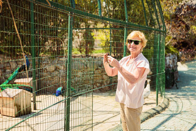 Elderly woman with mobile smartphone taking photo in zoo