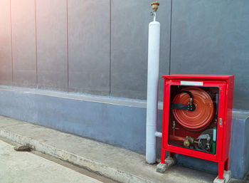 Red fire hydrant against wall in city