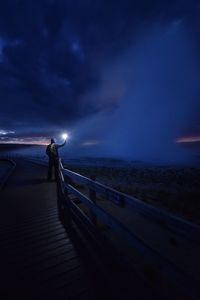Man standing on pier over sea against sky