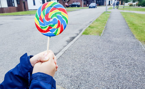 Low section of person holding multi colored candy