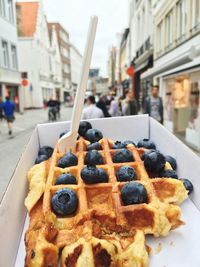 Close-up of waffle with blueberries in box over city street