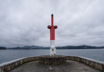 Lighthouse by sea against sky