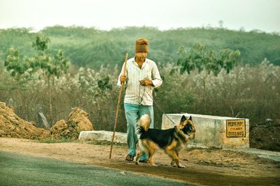 Man with dog standing by plants