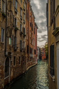 Canal amidst buildings in city against sky