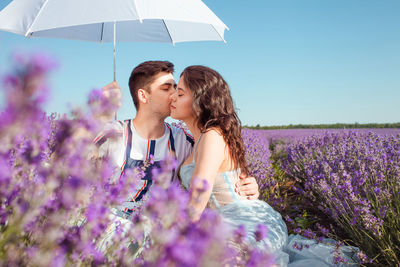 A couple in love under a white umbrella on a lavender field love