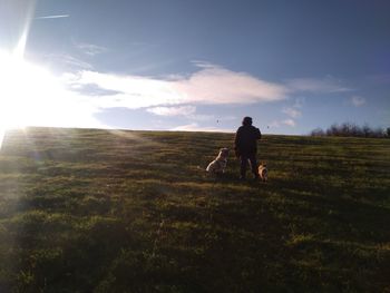 Rear view of man with dog on field against sky