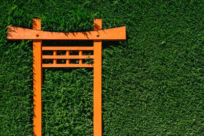 An orange torii gate in a garden hedge.