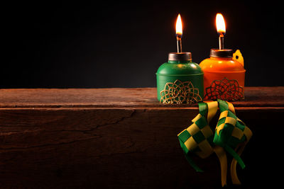 Close-up of illuminated lighting equipment on table against black background