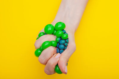 Close-up of hand holding multi colored yellow background