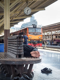 People at railroad station by building against sky