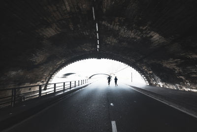 Rear view of man walking in tunnel