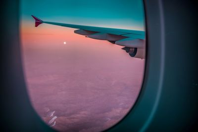 Close-up of airplane wing against sky during sunset