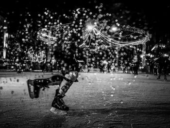 Ice skating outdoors during winter with lights in the background 