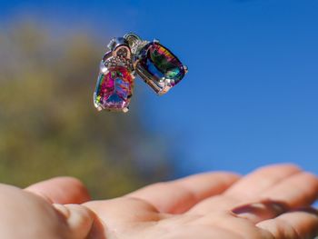 Cropped hand under earrings against sky