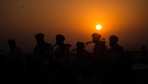 Silhouette people against sea during sunset